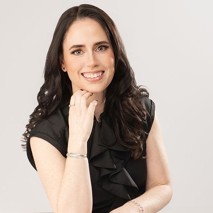 Smiling woman in black top, hand on chin