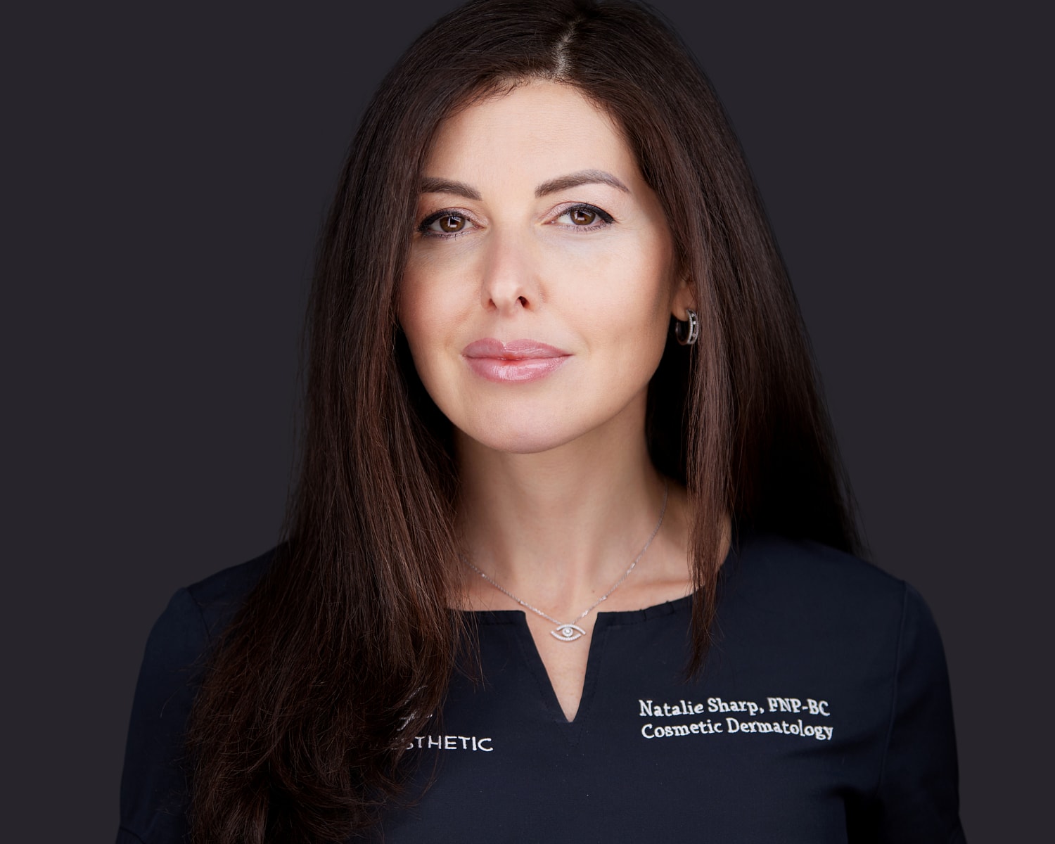 Cosmetic dermatologist with long hair and neutral expression.