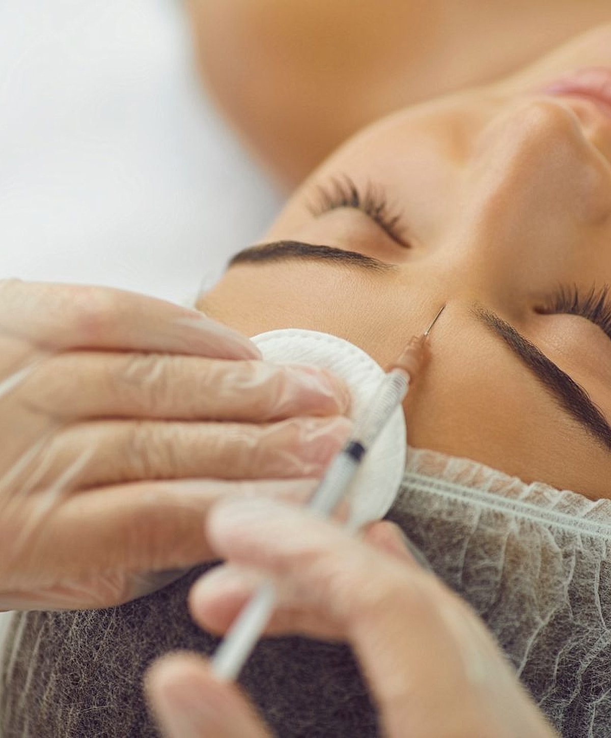 Woman receiving cosmetic injection treatment on forehead.