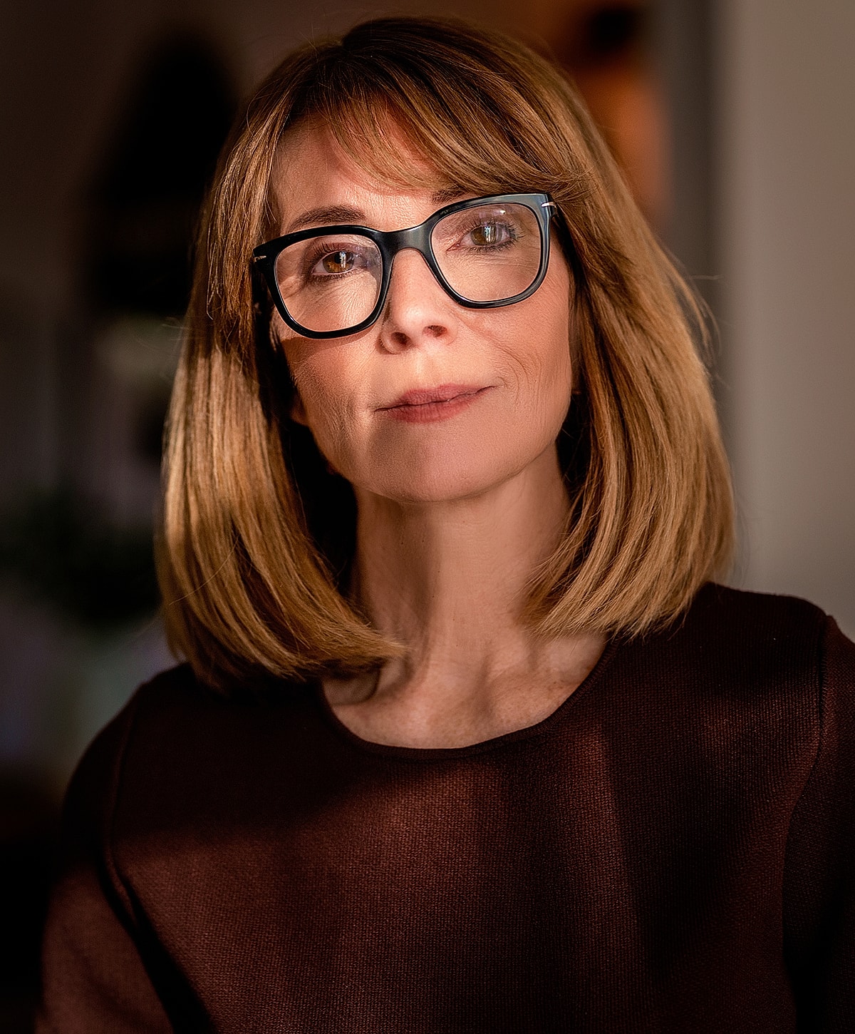 Woman with glasses in warm lighting portrait.