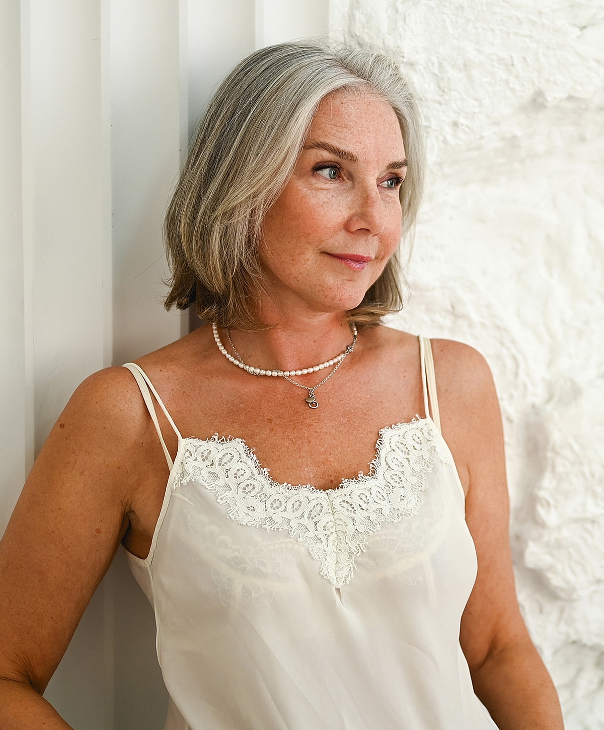 Woman with gray hair in light lingerie top.