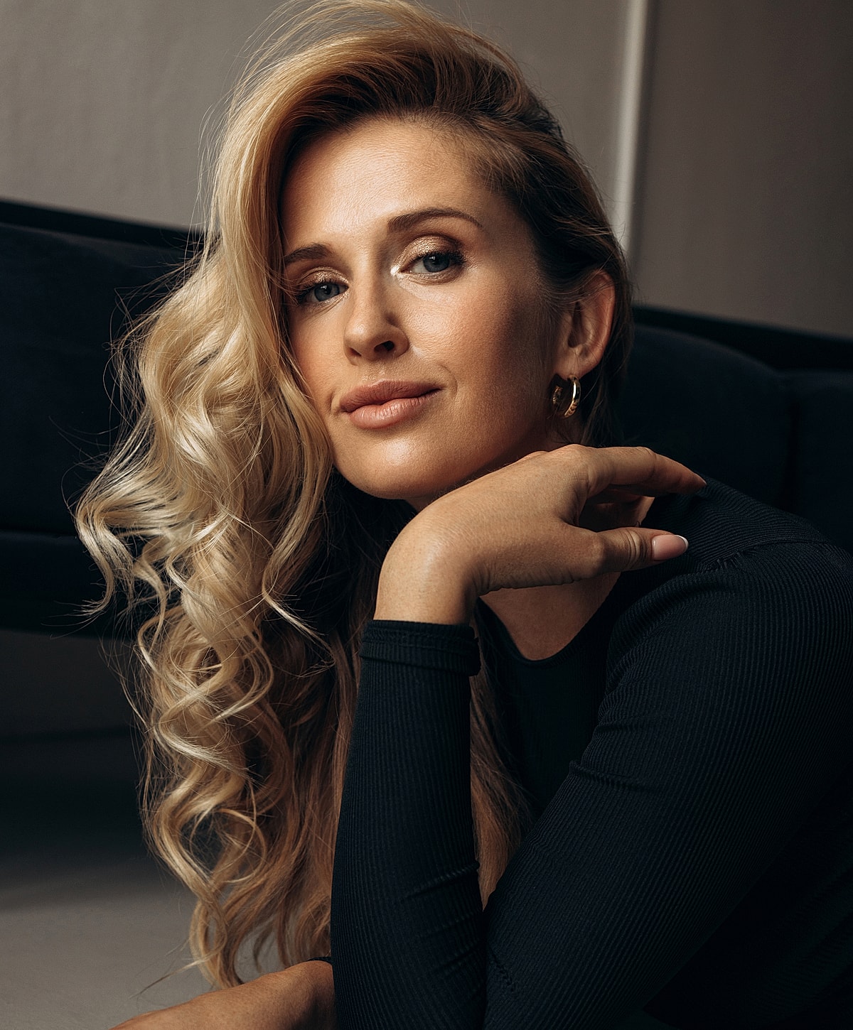 Woman with wavy blonde hair posing thoughtfully.