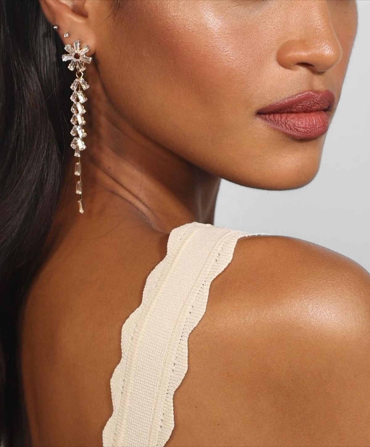 Model showcasing elegant statement earrings and smooth skin.