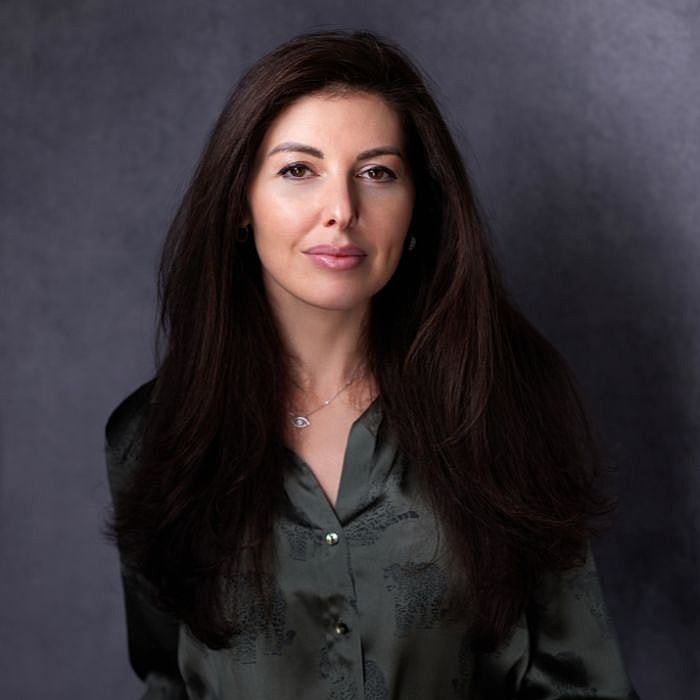 Woman with long hair in dark blouse portrait.