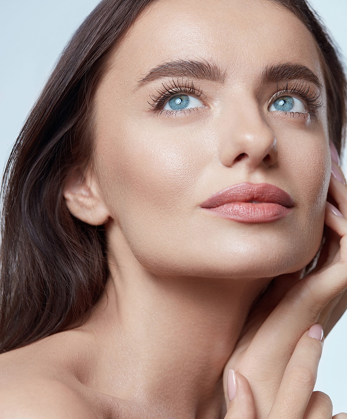 Close-up of woman with blue eyes and glowing skin.
