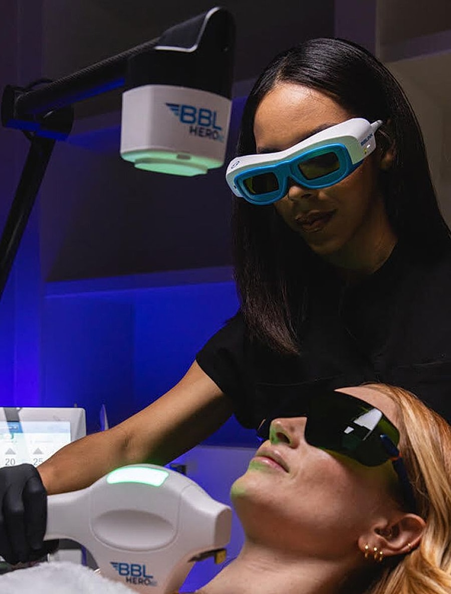 Woman receiving BBL laser treatment with technician.