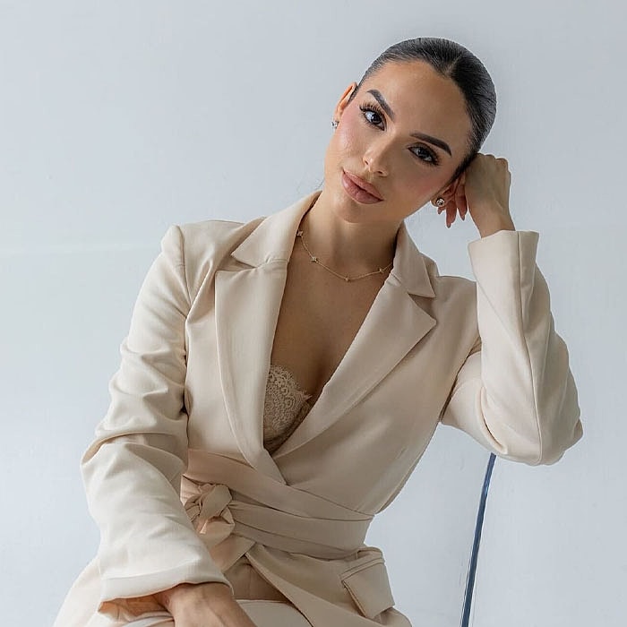 Woman in elegant beige outfit posing thoughtfully.
