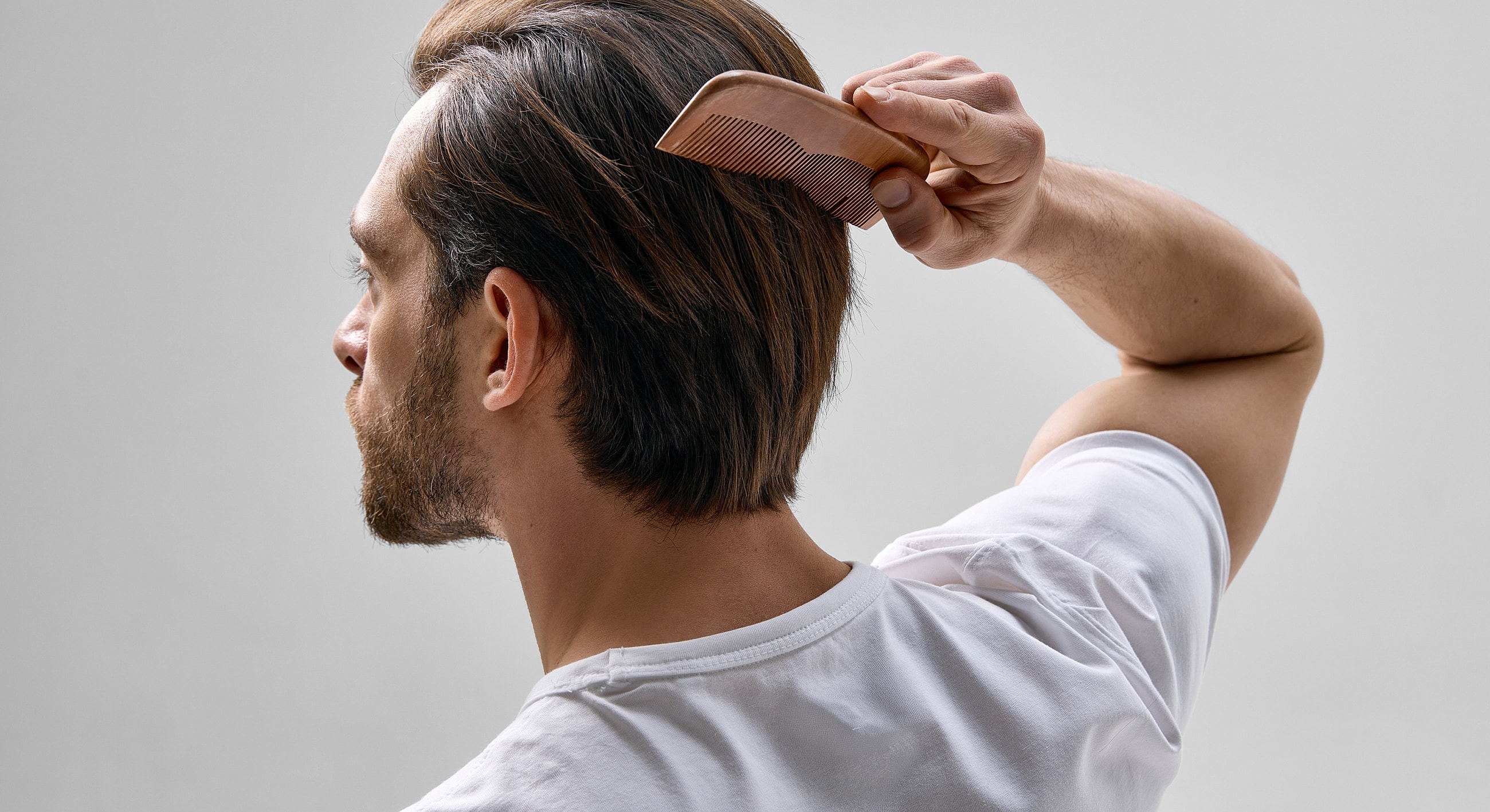 Man combing his hair from behind.