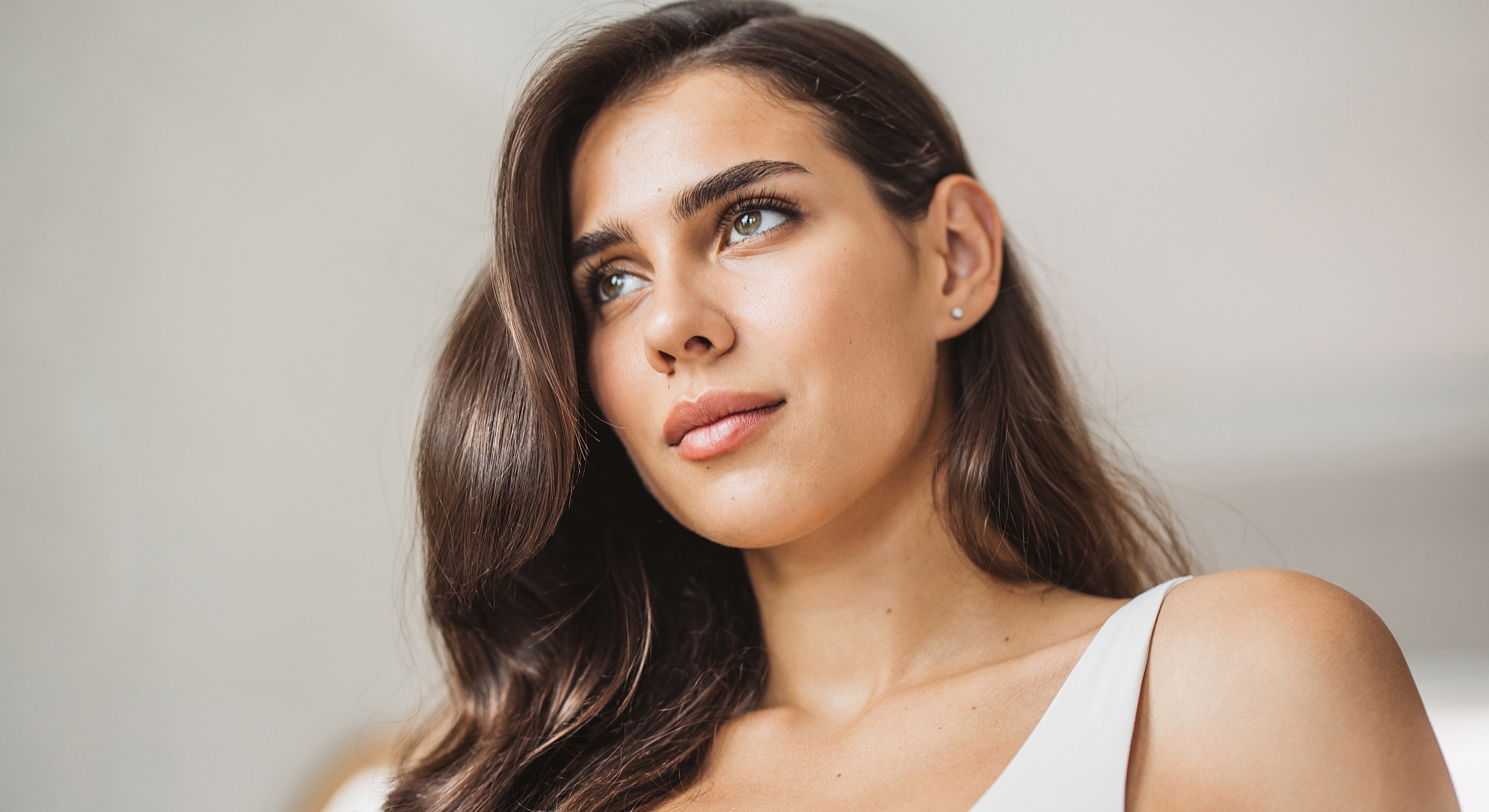 Woman with long hair looking thoughtfully upwards.