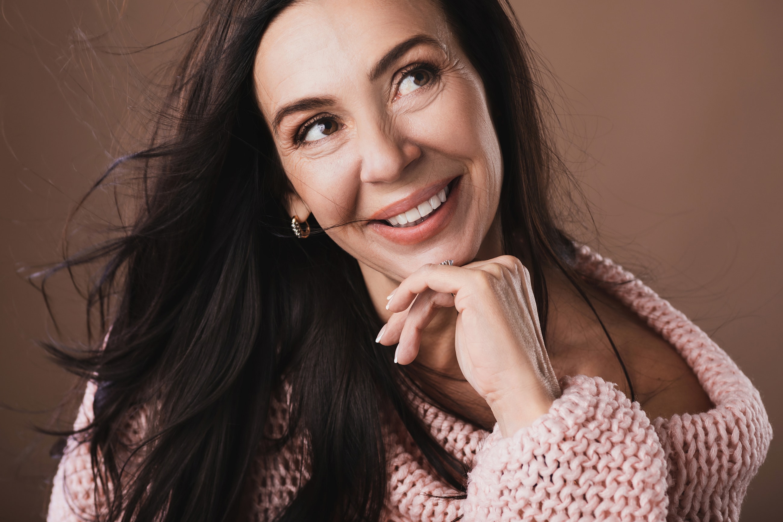 Woman smiling with wind-swept hair and sweater.