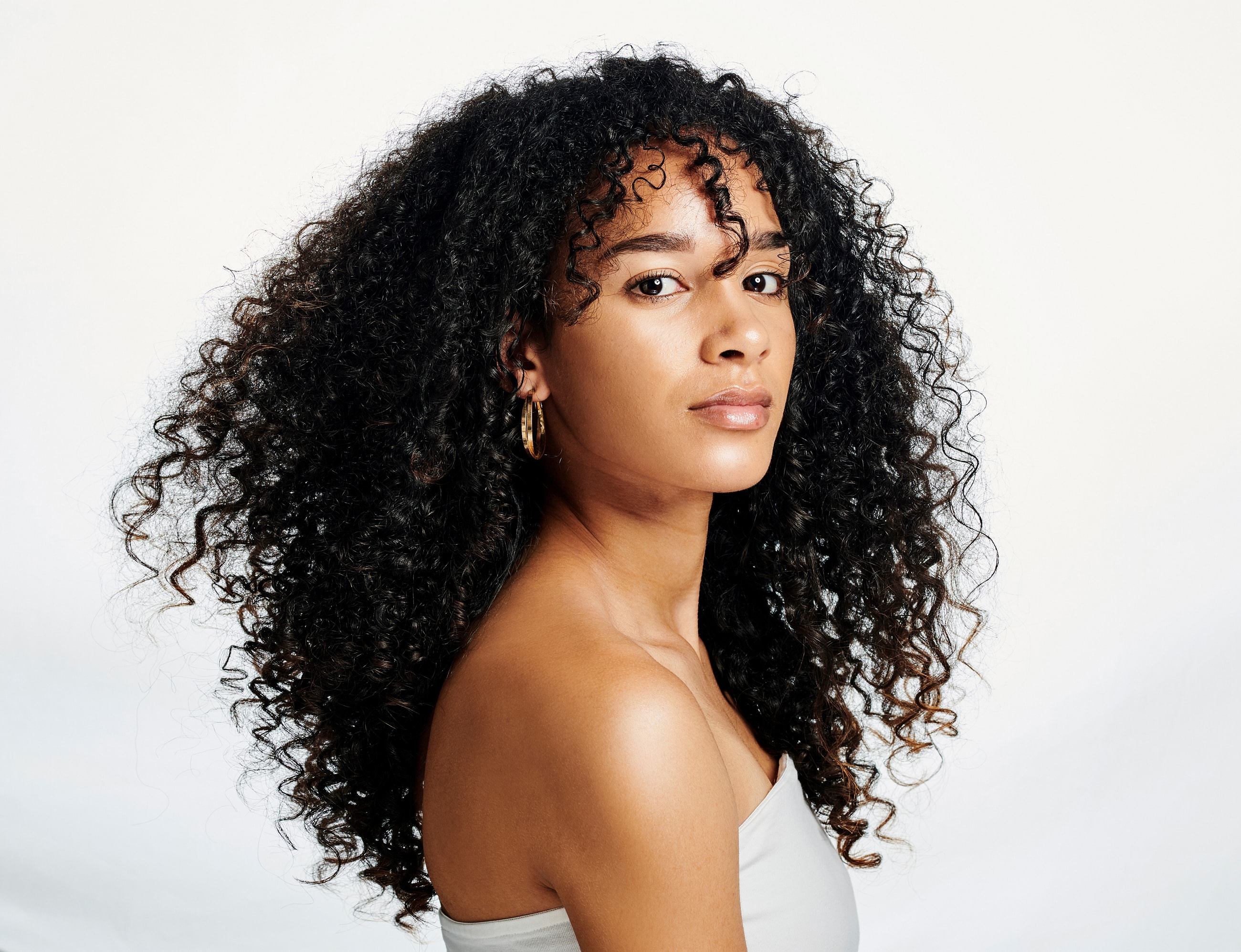 Woman with curly hair against a white background.