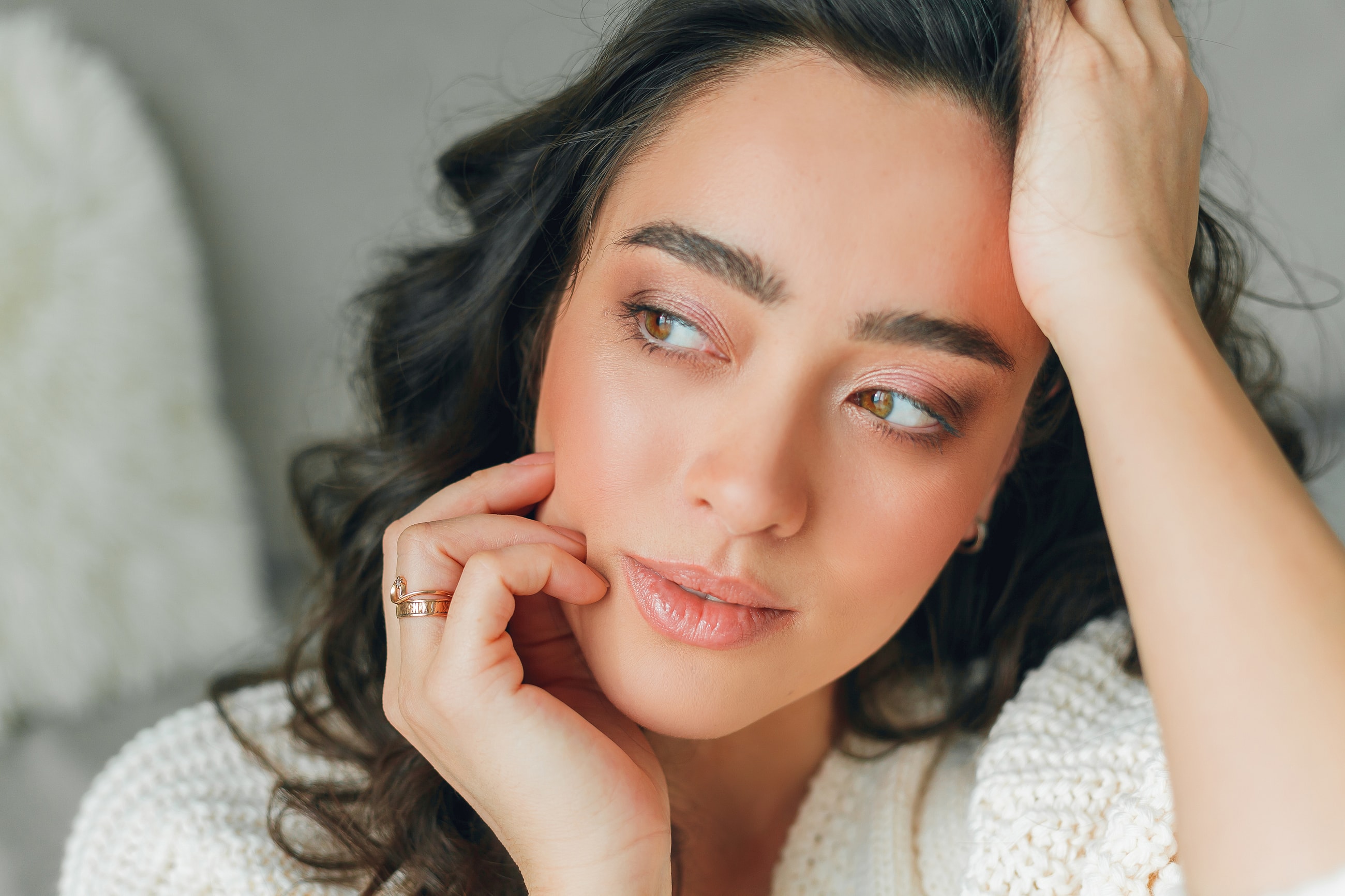 Woman looking thoughtfully with hand on face.