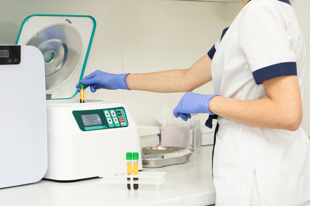 Medical professional processing PRF samples using a centrifuge in a clinical setting.