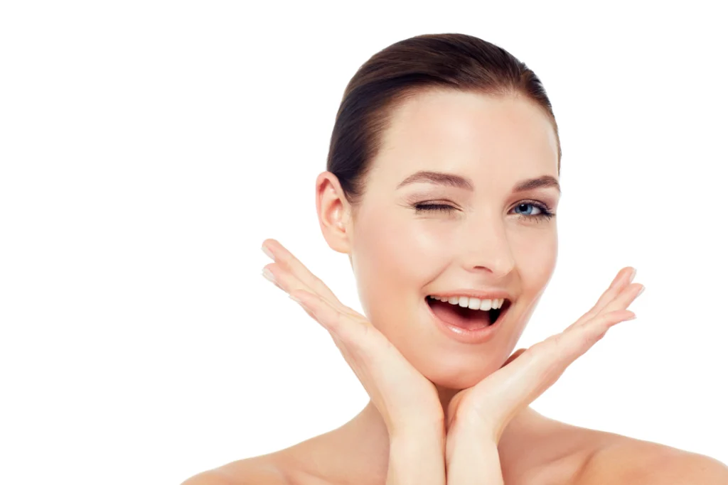 A happy young woman winking and smiling, showcasing her smooth, wrinkle-free skin after Jeuveau treatment.