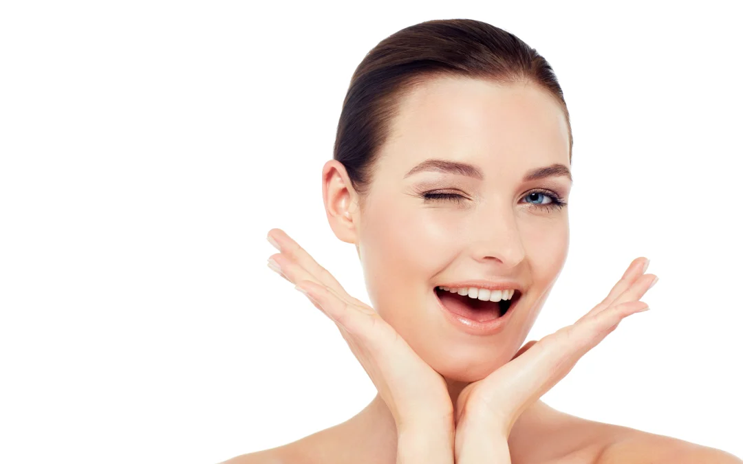 A happy young woman winking and smiling, showcasing her smooth, wrinkle-free skin after Jeuveau treatment.