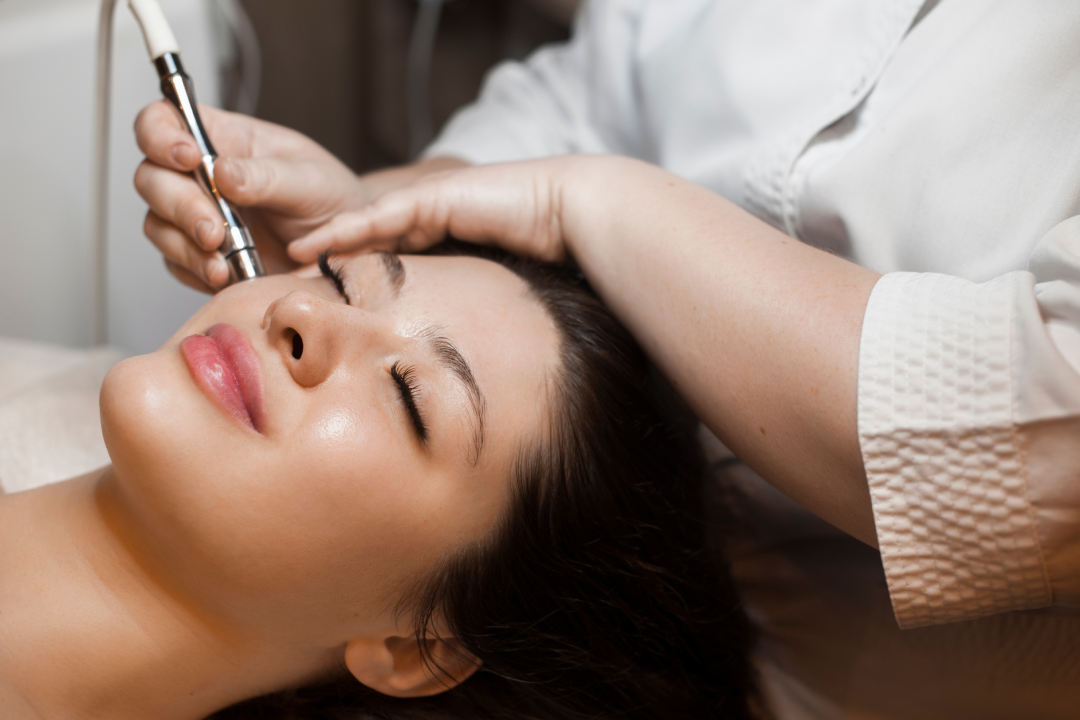 A skincare professional performing RF microneedling on a woman’s face during a clinical anti-aging treatment session.