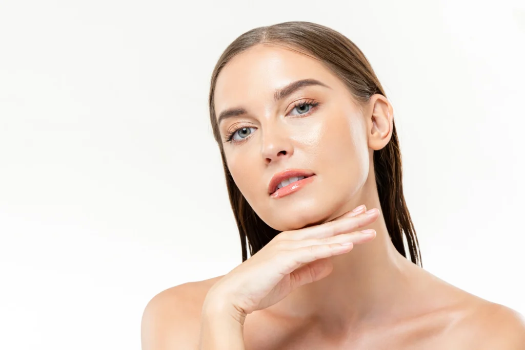 Woman with smooth-looking skin resting her chin on her hand against a light background