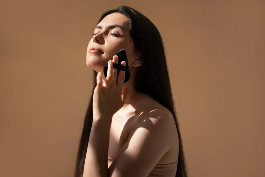 Person gently presses a skincare applicator against the jawline with eyes closed.